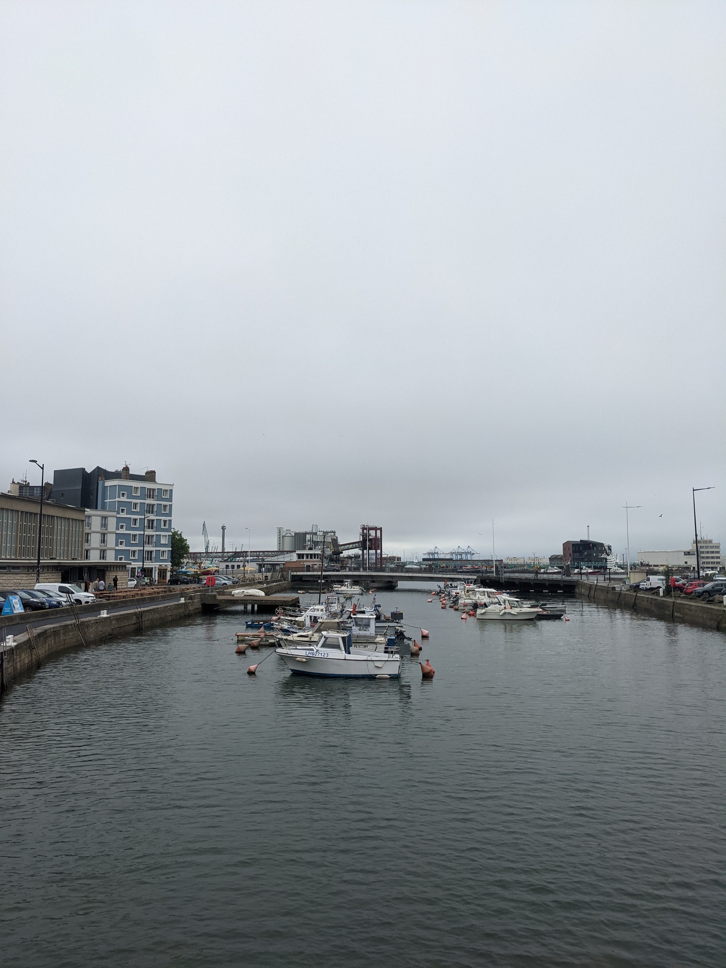 Vue sur un bassin du port du Havre a maree haute. Ciel gris et de batiments en beton autours.